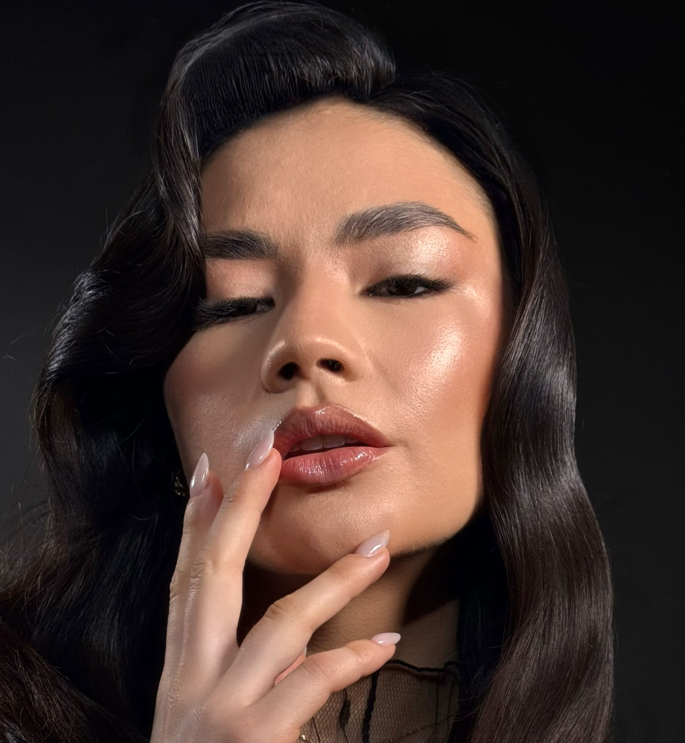 Primer plano del rostro de una mujer con piel con pecas, labios brillantes, ojos azules y cabello rizado rojo.